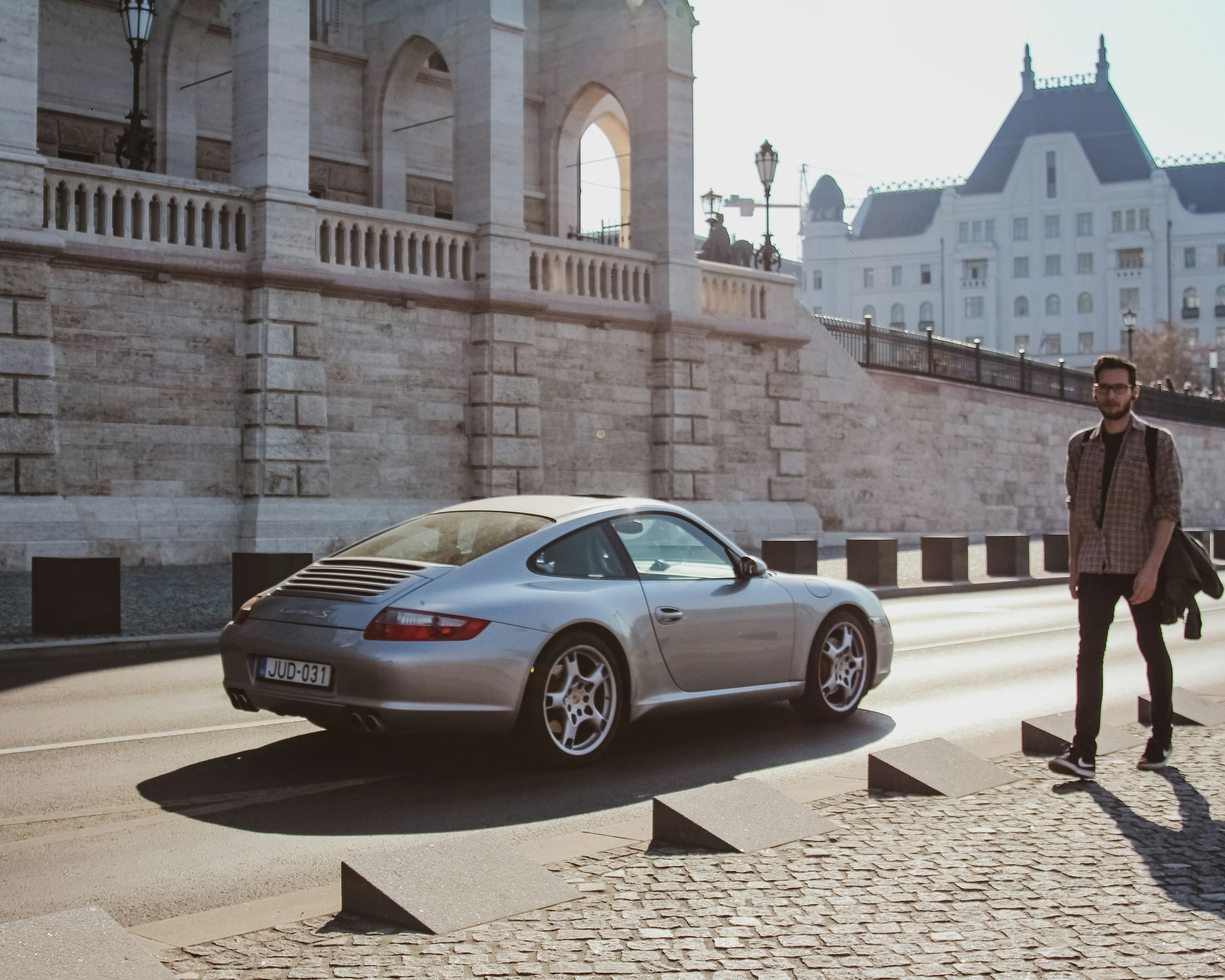 man walking near silver coupe on road